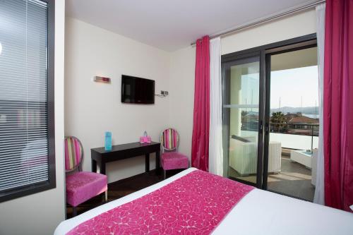 勒拉旺杜巴普迪斯丁酒店的一间卧室配有一张床和两张粉红色的椅子
