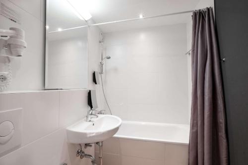柏林利希腾贝格舒适酒店的白色的浴室设有水槽和浴缸。