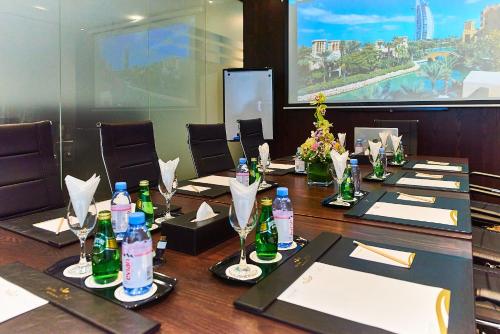 迪拜Rose Park Hotel - Al Barsha, Opposite Metro Station的一间会议室,里面配有长桌子和瓶子