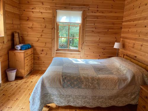 百利科内尔Riverside log cabin的木制客房内的一间卧室,配有一张床