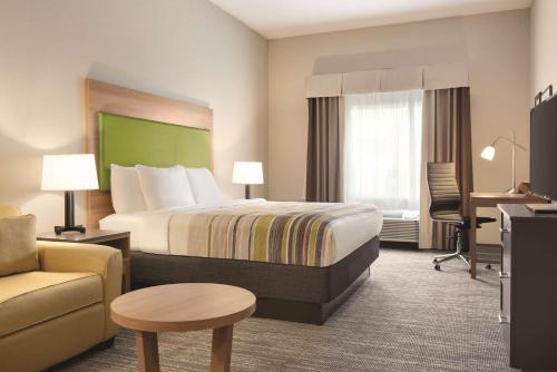 格林斯伯勒Country Inn & Suites by Radisson, Greensboro, NC的酒店客房配有一张床、一把椅子和一张书桌