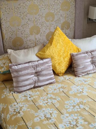 塔特舍尔Mini lodge hot tub hols at Kingfisher Court的床上有两张枕头,上面有黄色枕头