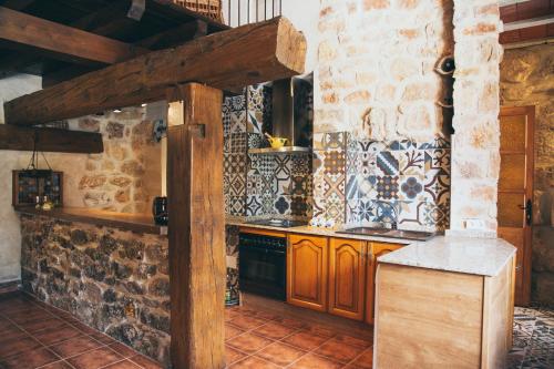 El PedernosoCasa Rural La Salitrosa的厨房配有木制橱柜和石墙