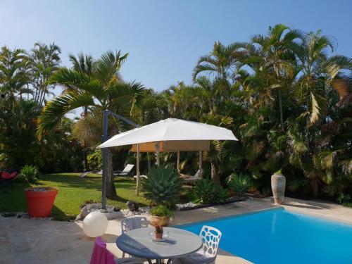 圣皮埃尔la maison du bonheur的一个带桌子和遮阳伞的庭院,毗邻一个游泳池