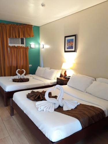 伊洛伊洛Sea Garden Resort Iloilo的两张床铺,位于酒店客房内,配有天鹅