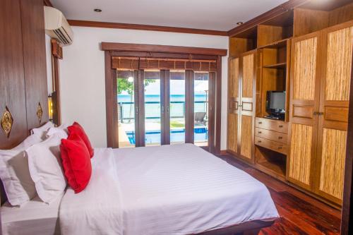 拉迈宝金波别墅的卧室配有白色的床和红色枕头