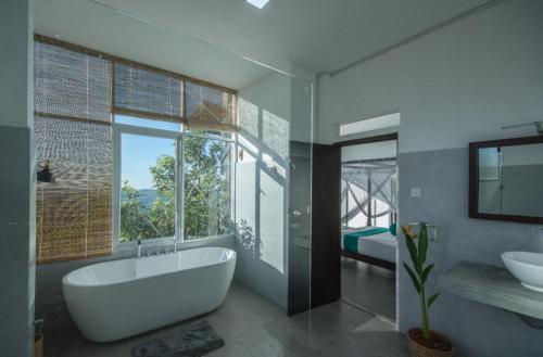 贝里胡罗亚Treehouse Chalets的带浴缸、水槽和窗户的浴室