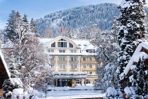 格施塔德乐格兰德贝尔维尤酒店的雪中一座大建筑,有雪覆盖的树木