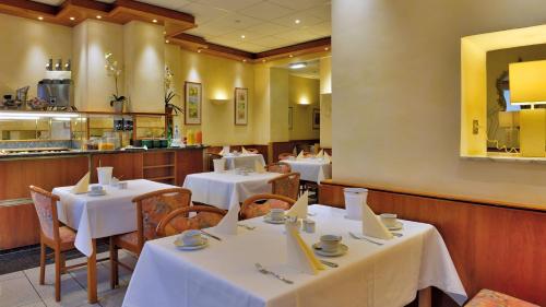 科隆依贝茨嘉利酒店的一间带白色桌椅的餐厅和一间厨房