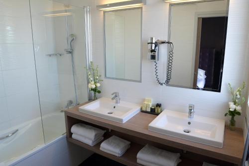 巴黎圣查尔斯酒店的浴室设有2个盥洗盆、淋浴和镜子。