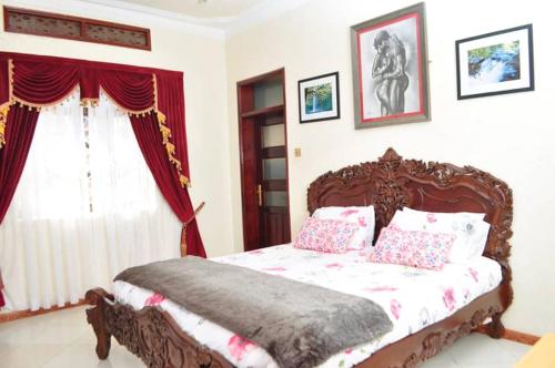 坎帕拉Plot 4 Kavuma Close的卧室配有带枕头的木床和窗户。