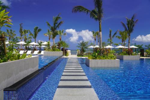 石垣岛FUSAKI BEACH RESORT HOTEL & VILLAS的棕榈树和遮阳伞度假村的游泳池