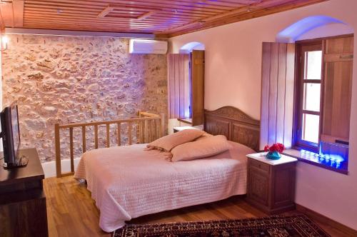 莫奈姆瓦夏阿达米斯酒店的一间卧室设有一张床和石墙