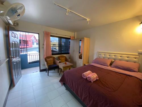 清迈班蓬潘公寓的卧室配有床、椅子和窗户。