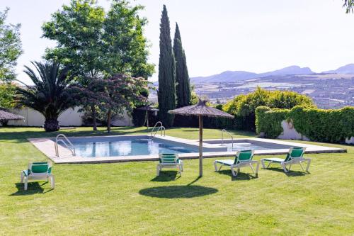 隆达Hotel Boutique Molino del Arco的一个带游泳池、椅子和遮阳伞的庭院
