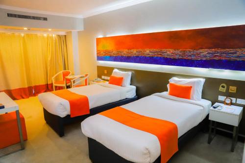 阿斯旺阿斯旺城市最大酒店的酒店客房设有两张床,墙上挂有绘画作品
