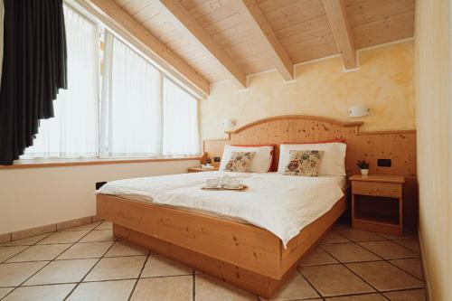 特伦托阿格瑞图尔法德阿迪杰酒店的一间卧室配有一张大床和木制床头板