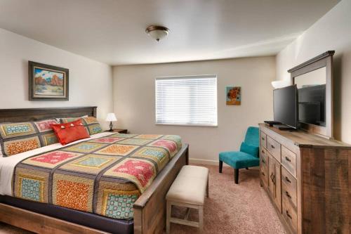 摩押5I Cozy Family Friendly Moab Condo的一间卧室配有一张床、一台电视和一把椅子