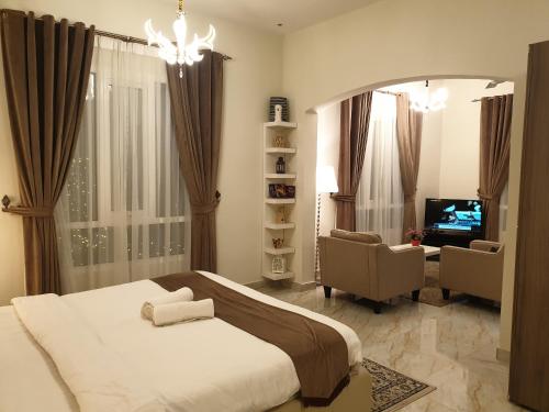 锡卜Muscat Royal Suites的一间卧室配有一张床、一台电视和一把椅子