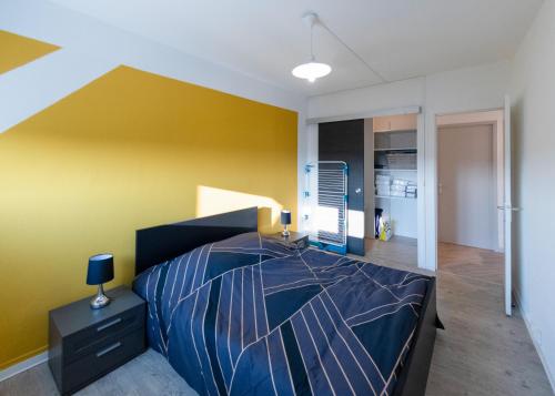 蒙贝利亚尔Appart'Hôtel - l'île en mouvement的一间卧室设有一张床和黄色的墙壁