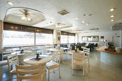 泉佐野康库太阳丰酒店的一间设有白色桌椅的餐厅和一间酒吧