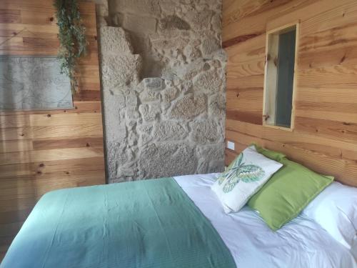 庞特维德拉Hospédate Pontevedra的石墙房间内的一张床位