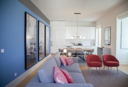 里斯本FLH Augusta's Arch Design Apartment的客厅配有蓝色的沙发和红色的椅子