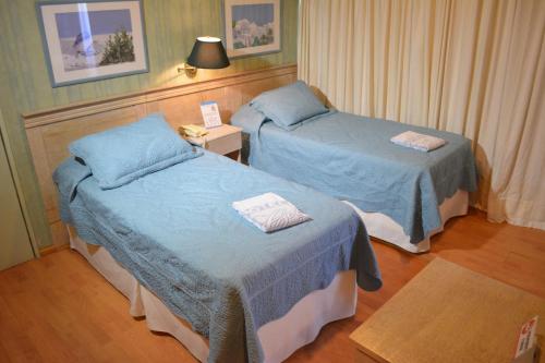 萨尔托Hotel Solar del Acuario的酒店客房设有两张床和一张桌子。