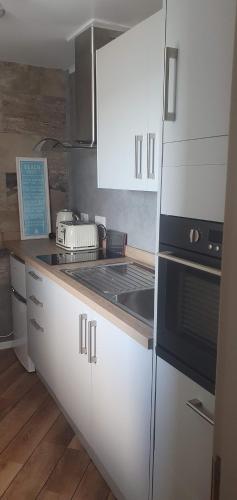 瑟索3 Braehead的厨房配有白色橱柜和炉灶烤箱。