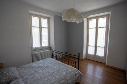 托雷佩利切Appartamento con vista a Torre Pellice的一间卧室设有一张床和两个窗户。