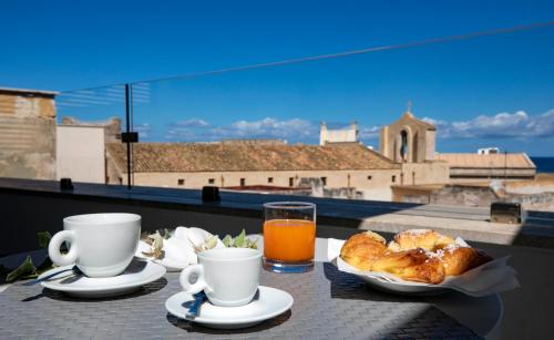 特拉帕尼Azzoli Trapani - Apartments&Skypool - Adults Only的一张桌子,上面放着咖啡、羊角面包和一杯橙汁