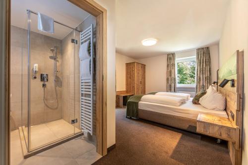 贝希特斯加登Home-Hotel Salzberg的一间卧室设有一张床和一个玻璃淋浴间