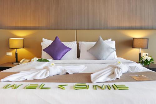 曼谷美達廊曼機場酒店的一张配有白色床单和紫色枕头的大床
