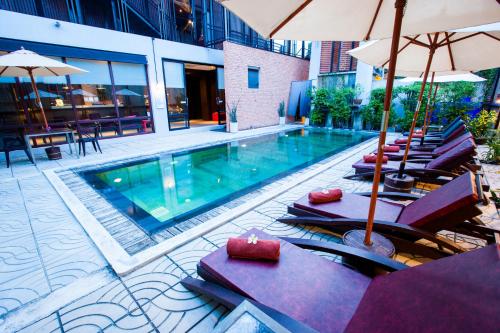 拉迈苏梅岛艾姆尼提阿帕图尔酒店的一座带椅子和遮阳伞的游泳池位于一座建筑旁边