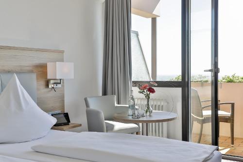 圣马丁Arens Hotel 327mNN的酒店客房带一张床、一张桌子和椅子