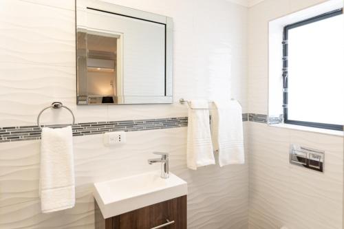杰弗里湾Grand House Lodge And SPA Jeffreys Bay的白色的浴室设有水槽和镜子