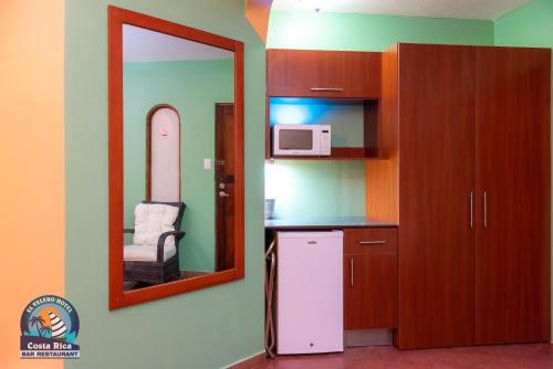 普拉亚埃尔莫萨Hotel El Velero的一间带镜子和冰箱的小厨房