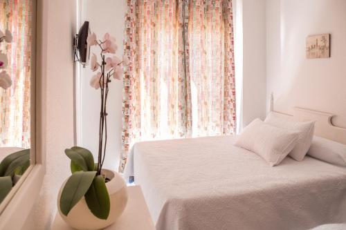 卡沃内拉斯Pensión Las Palmas的卧室配有白色的床和花瓶