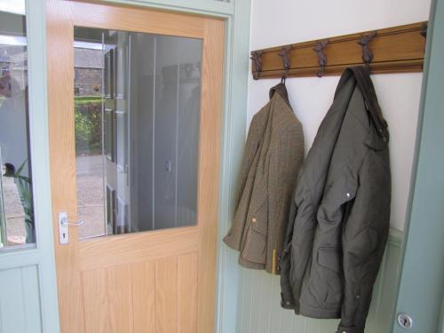 阿伯劳尔Bankhouse B&B的两件夹克挂在门边的门