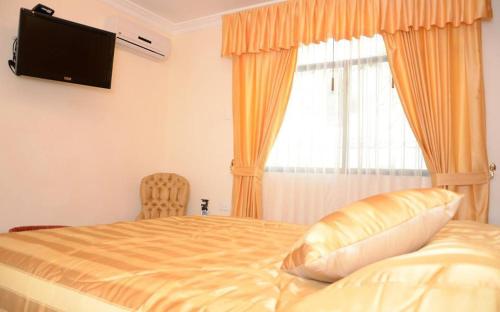 瓜亚基尔瓜亚斯河畔酒店的一间卧室设有一张带电视和窗户的床。