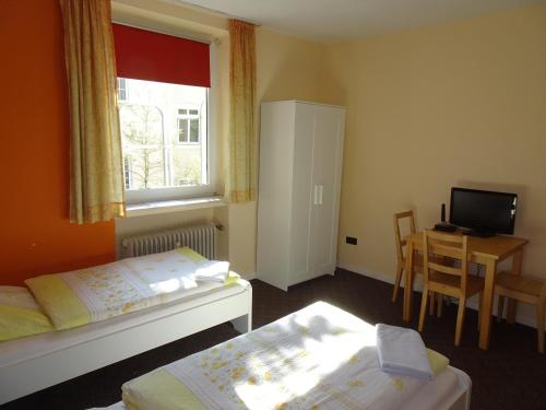 杜塞尔多夫格鲁佩罗宾馆的一间卧室设有两张床、一张桌子和一个窗口。
