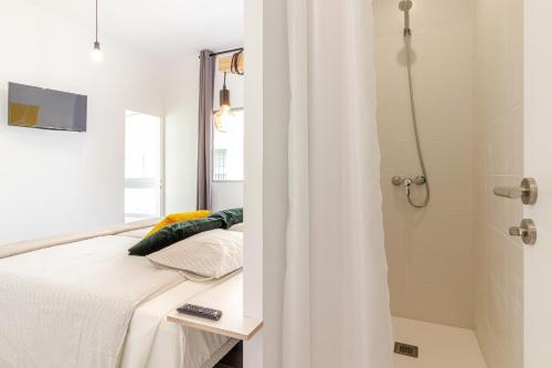 大加那利岛拉斯帕尔马斯Flatguest Paez Suites的一间卧室配有一张床和淋浴
