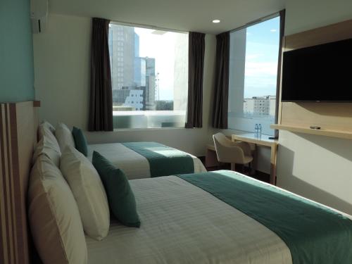 韦拉克鲁斯Hotel Plaza Sol Veracruz的酒店客房设有两张床和大窗户。