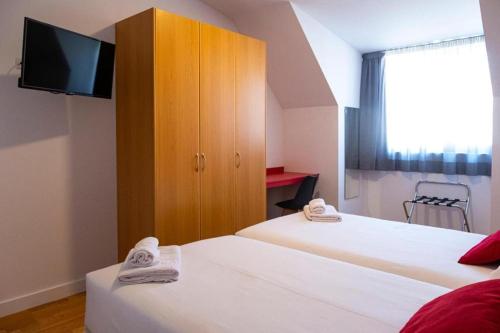 纳龙Spa Suites Odeón的客房设有两张床和带电视的橱柜。
