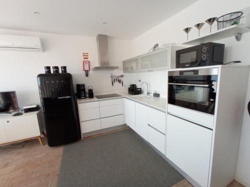 圣卢西亚岛Flamingo Beach House的厨房配有白色橱柜和黑色冰箱。