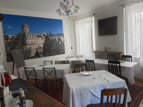 特伦托B&B La Loggia Del Castello的餐厅配有白色的桌椅和墙上的绘画作品