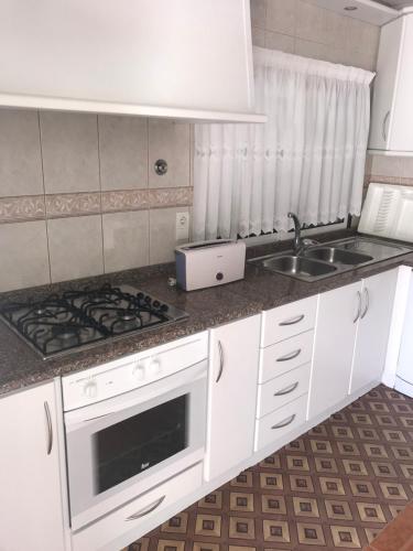 吉尔斯Casa Lola Principe的白色的厨房设有水槽和炉灶。