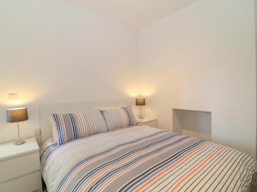 廷茅斯Samphire的一间卧室配有一张带条纹床罩的床和两盏灯。