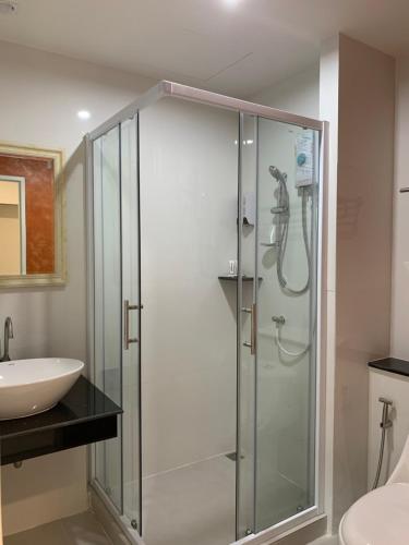 曼谷Icare Residence & Hotel的一个带水槽的玻璃淋浴间