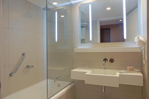 蒙得维的亚Dazzler by Wyndham Montevideo的一间带玻璃淋浴和水槽的浴室